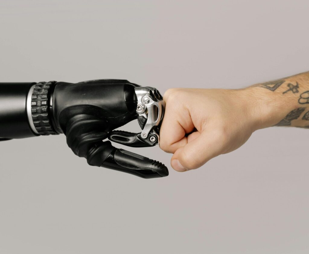 Close-up of a human fist bumping a prosthetic hand, symbolizing technology and human connection.